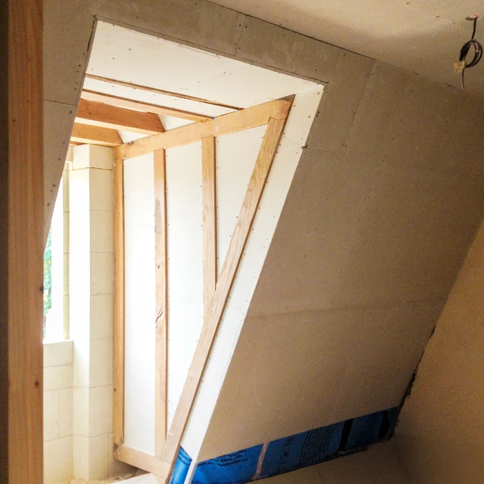 Intérieur en construction avec charpente bois apparente, poutres et chevrons visibles