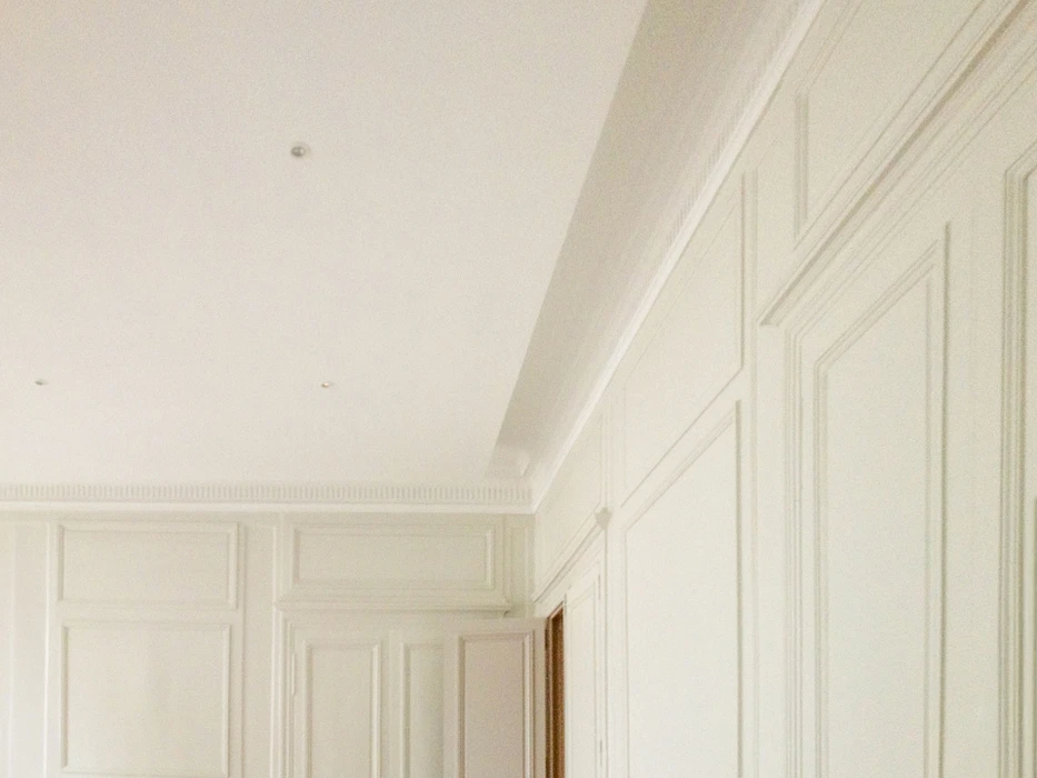 Salon moderne avec canapé d'angle beige face à une cheminée encastrée