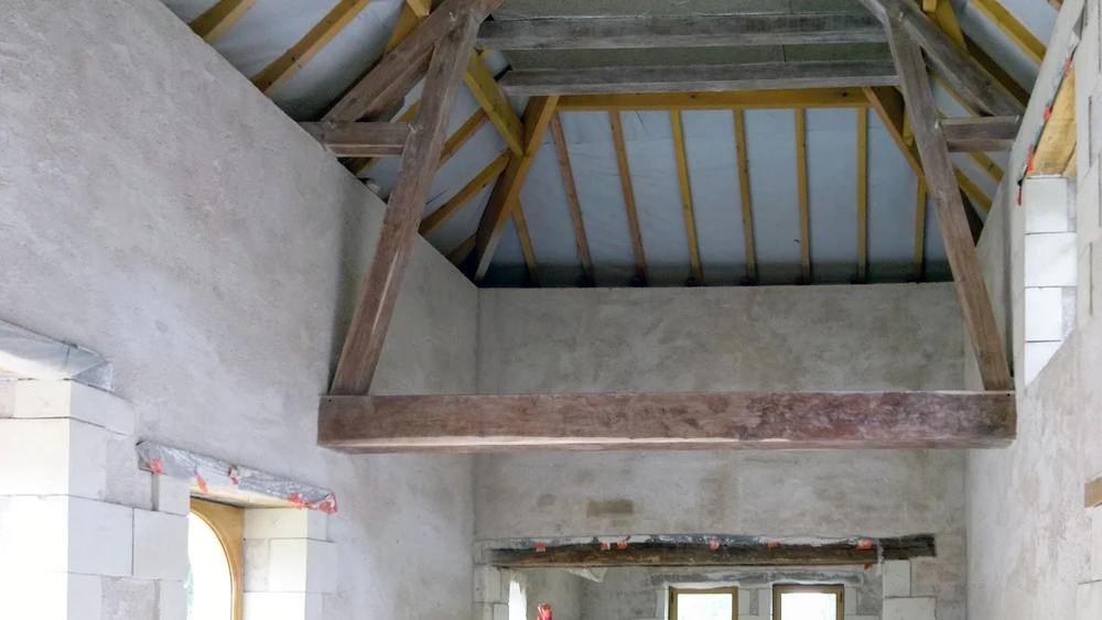 Salon moderne avec canapé d'angle gris, fauteuils en cuir orange et cheminée à gaz encastrée