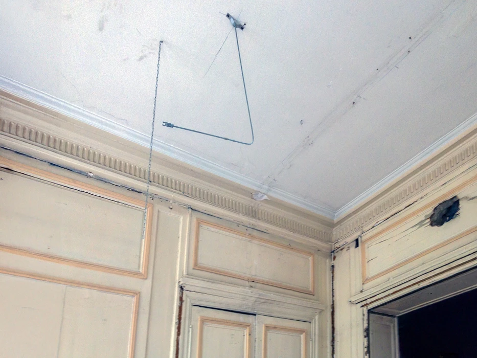 Salon moderne avec canapé d'angle gris, fauteuil assorti et cheminée contemporaine à foyer fermé