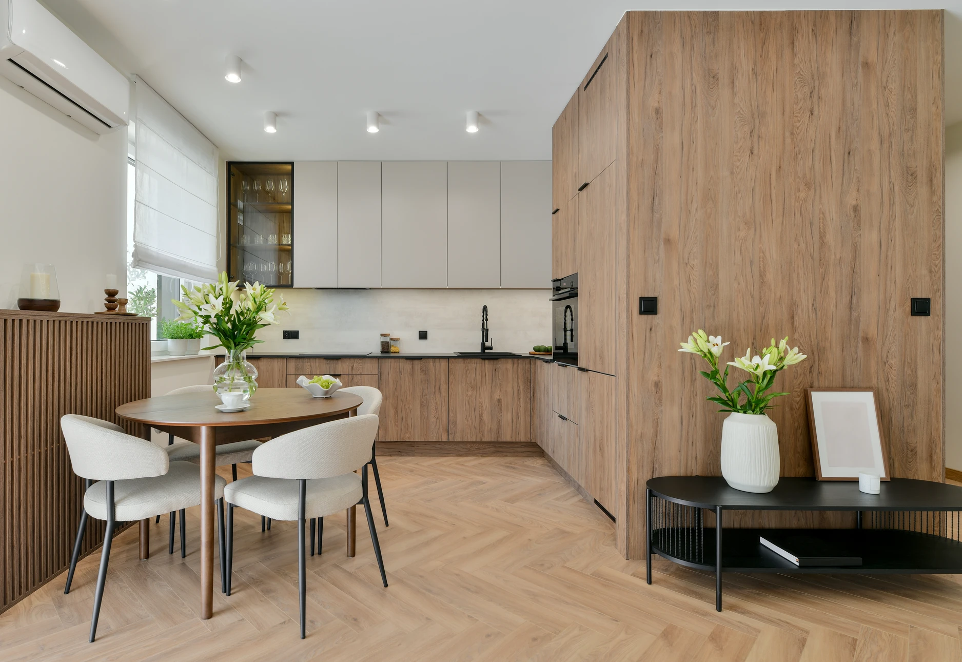Salon spacieux avec cheminée en marbre blanc et manteau décoratif, murs peints en vert olive, plafond blanc avec poutres apparentes et éclairage encastré