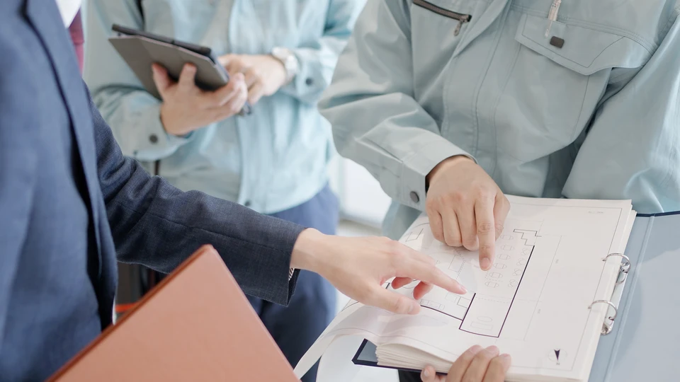 Couple assis sur parquet examine plans architecturaux dans salon en r&eacute;novation